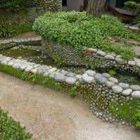 Vodné žriedlo napájajúce kaskády z okruhliakov v symbióze s machmi a plazivou zeleňou (japonská záhrada, Francúzsko)